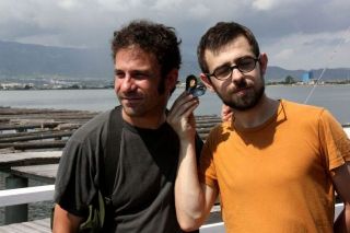 Los artistas sonoros Vicente Matamoros y Martín Ruido simulan escuchar el sonido de un mejillón - Autor: ACN / POBLADO, Laia